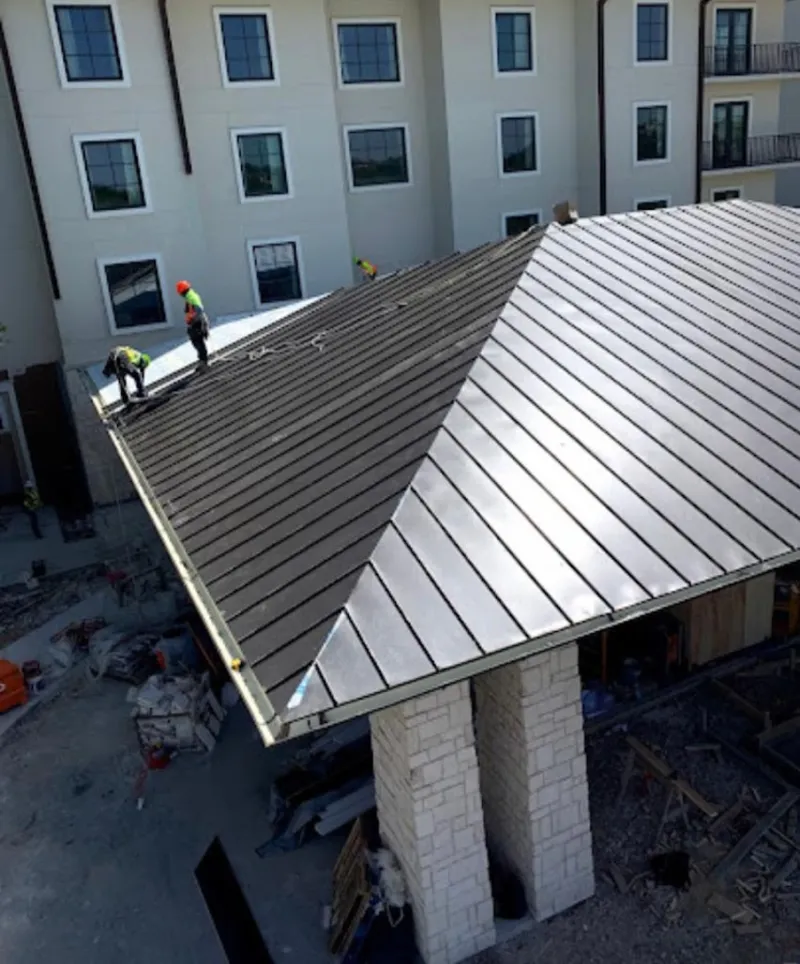 Crew installing standing seam metal roof panels on a commercial project in Westchester